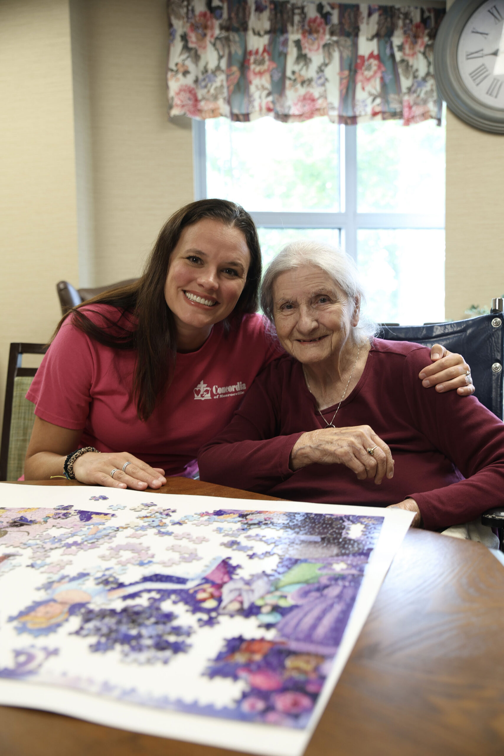 Two women smiling together, completing a puzzle.