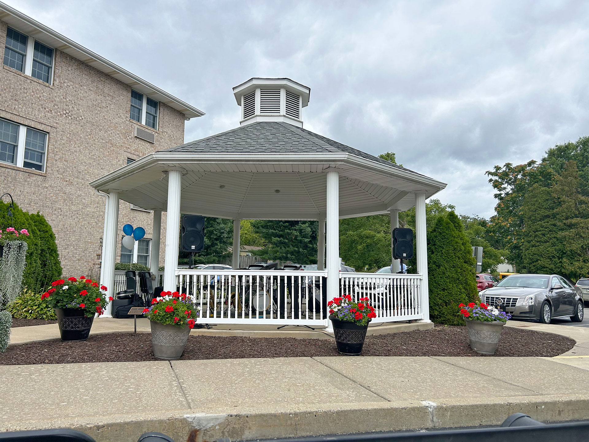 White gazebo with flower pots and gray clouds above.