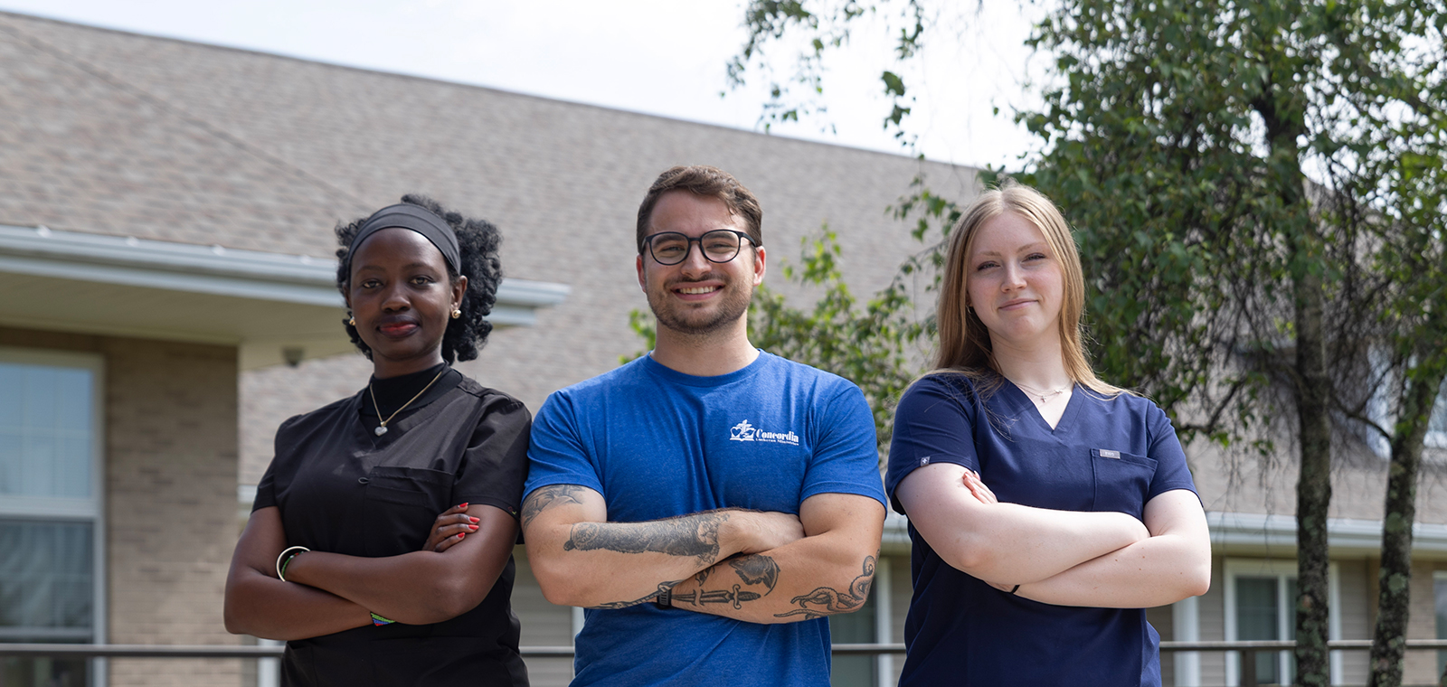 Three healthcare professionals posing outdoors, arms crossed confidently.