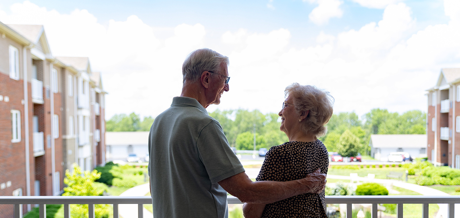 Elderly couple smiling at each other on a balcony.