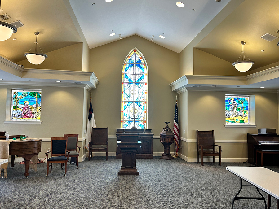 Bright room featuring stained glass windows and wooden furniture.