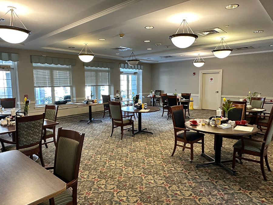 Bright dining area with tables, chairs, and breakfast items.