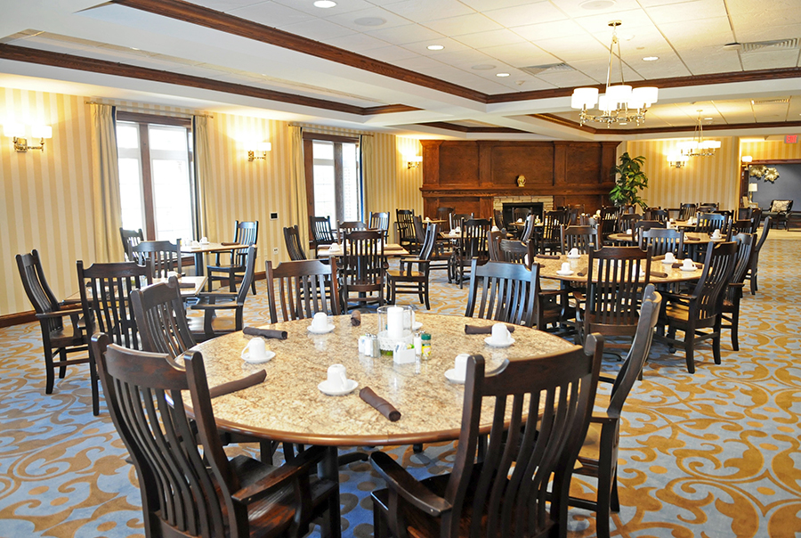 Empty dining area with tables, chairs, and a fireplace.
