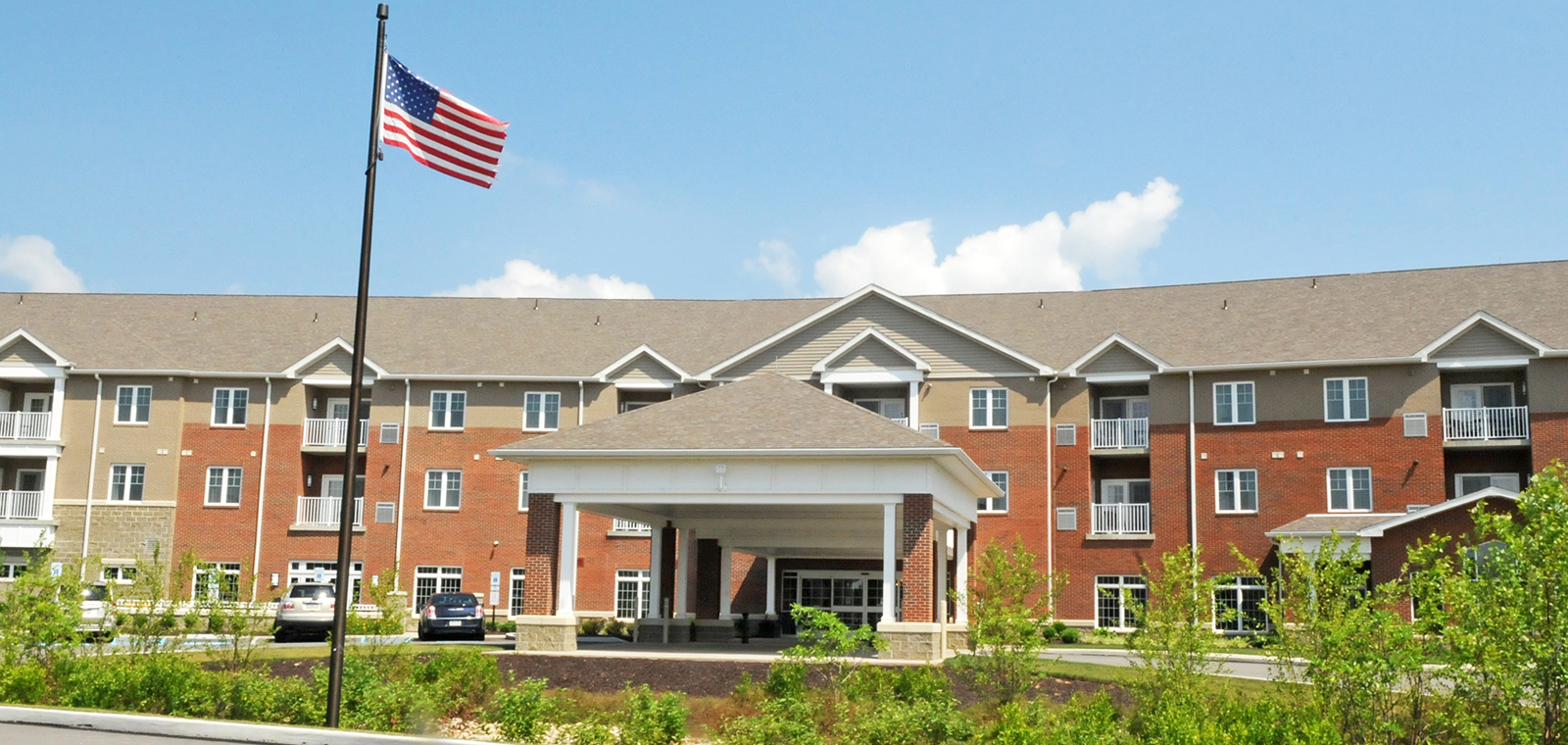 Residential building with American flag and landscaping in front.