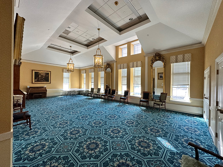 Elegant room with patterned carpet, chandeliers, and natural light.