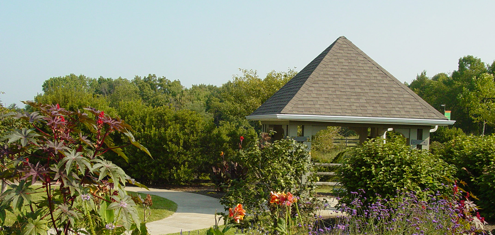 A gazebo surrounded by lush greenery and colorful flowers.