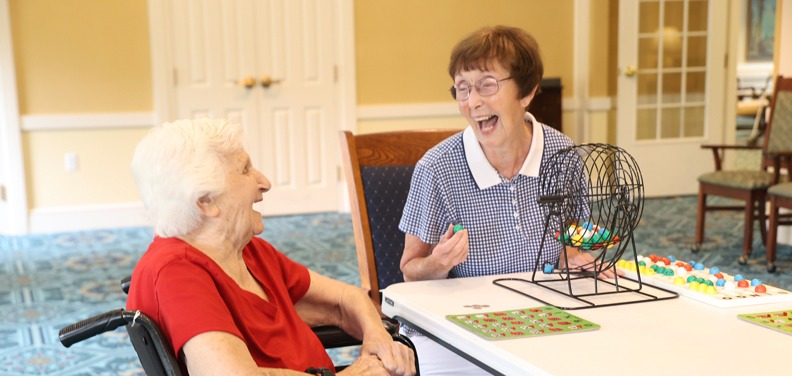 Two elderly women laughing during a bingo game.