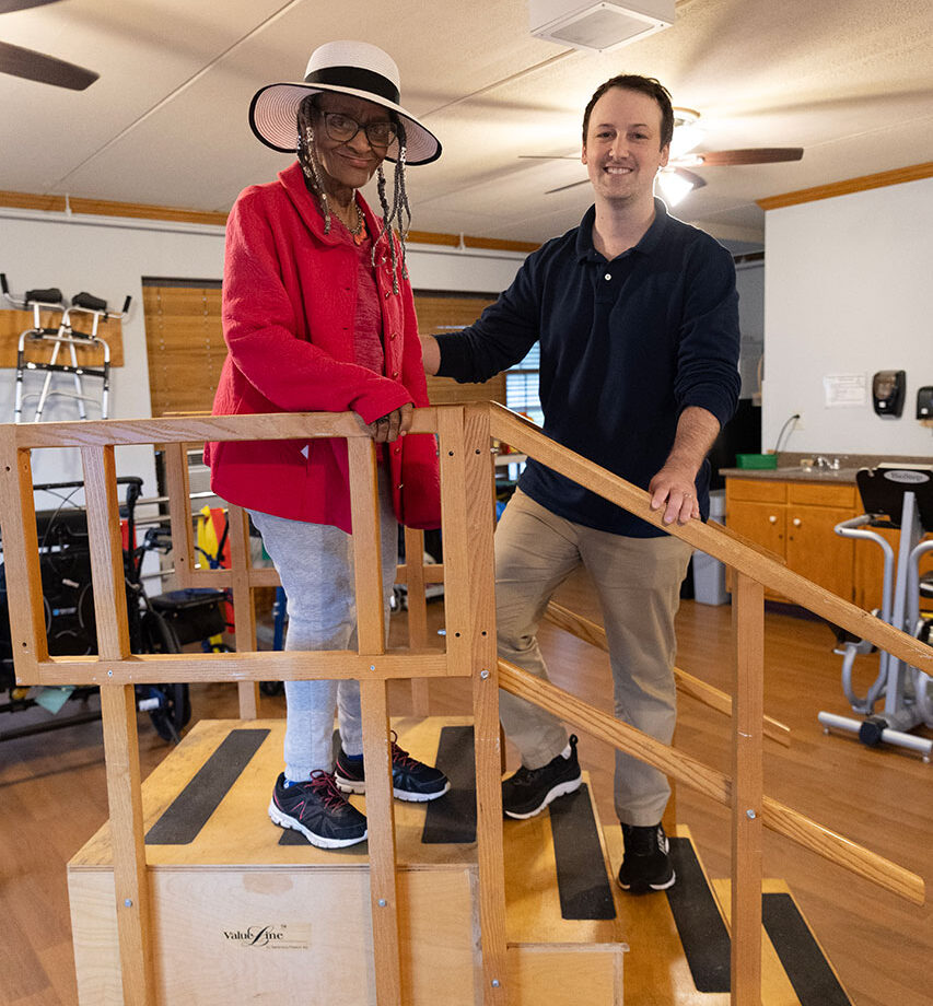 Two people on a wooden stair training equipment indoors.