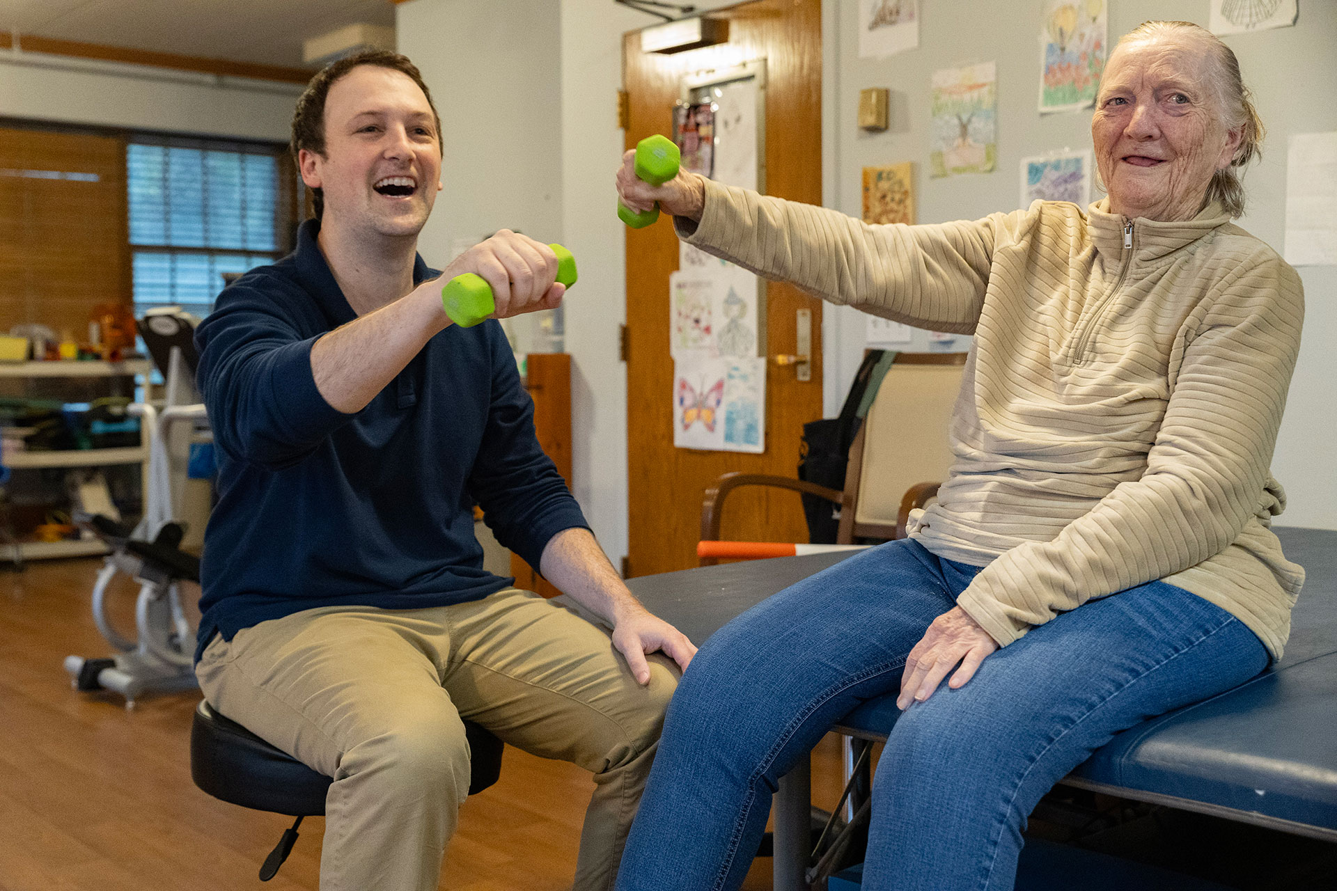 Man and woman exercising with weights, smiling and engaged.