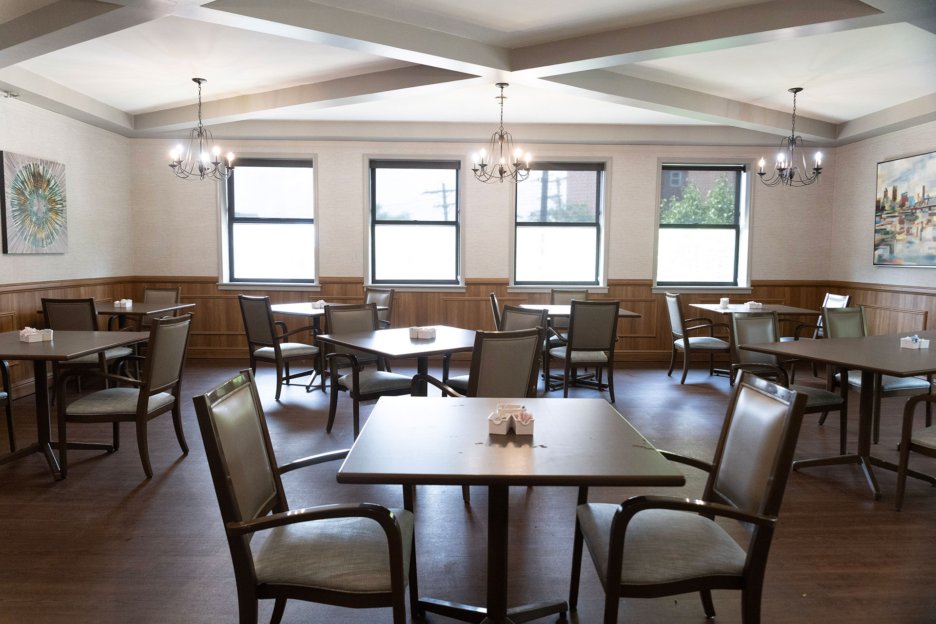 Empty dining room with tables, chairs, and decorative artwork.
