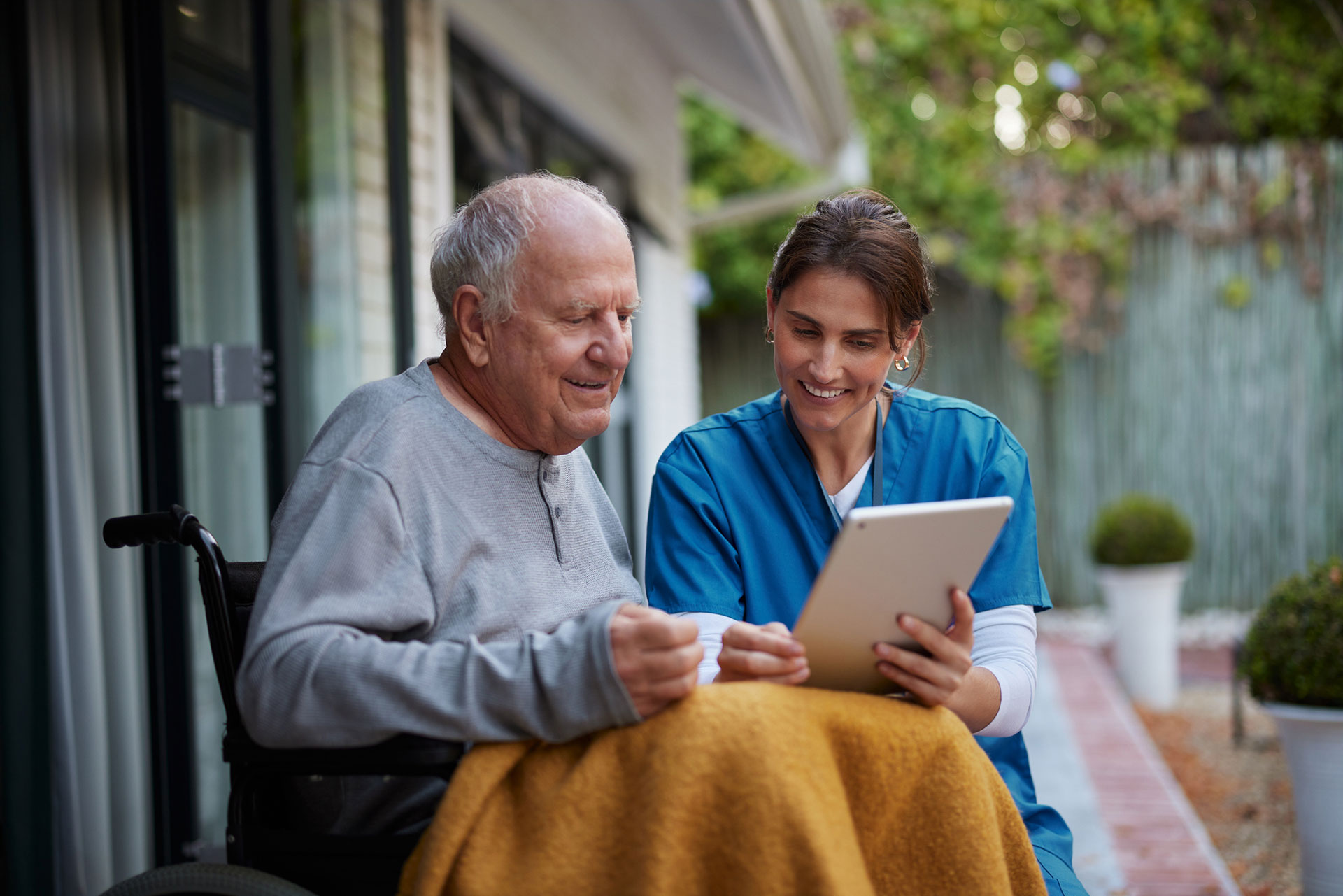 Nurse and elderly man enjoying time together with a tablet.