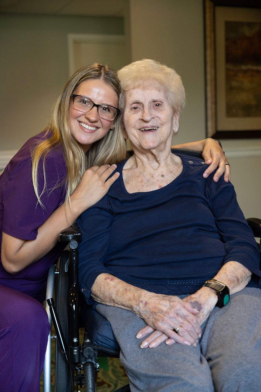 Smiling woman and elderly lady in a healthcare setting.