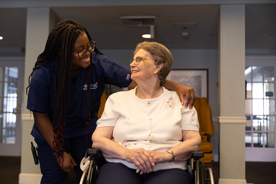 Caregiver and elderly woman share a warm, joyful moment.