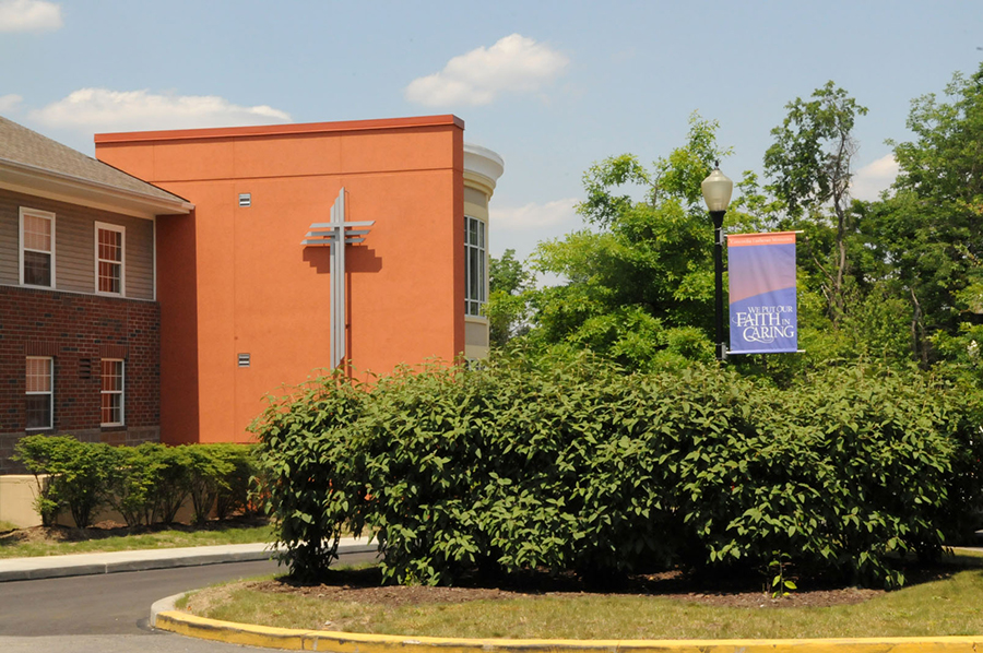 Building with cross and banner, surrounded by greenery.