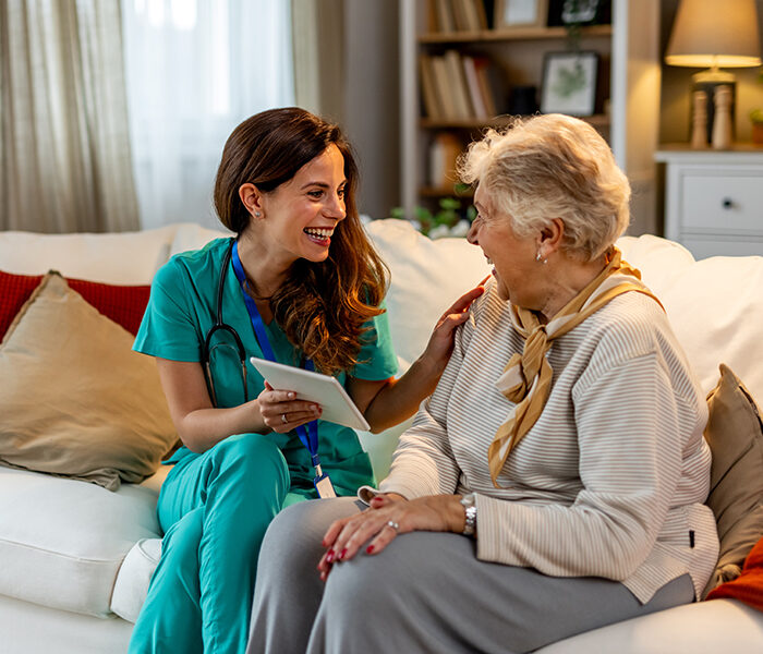 Healthcare professional and elderly woman sharing a joyful moment.
