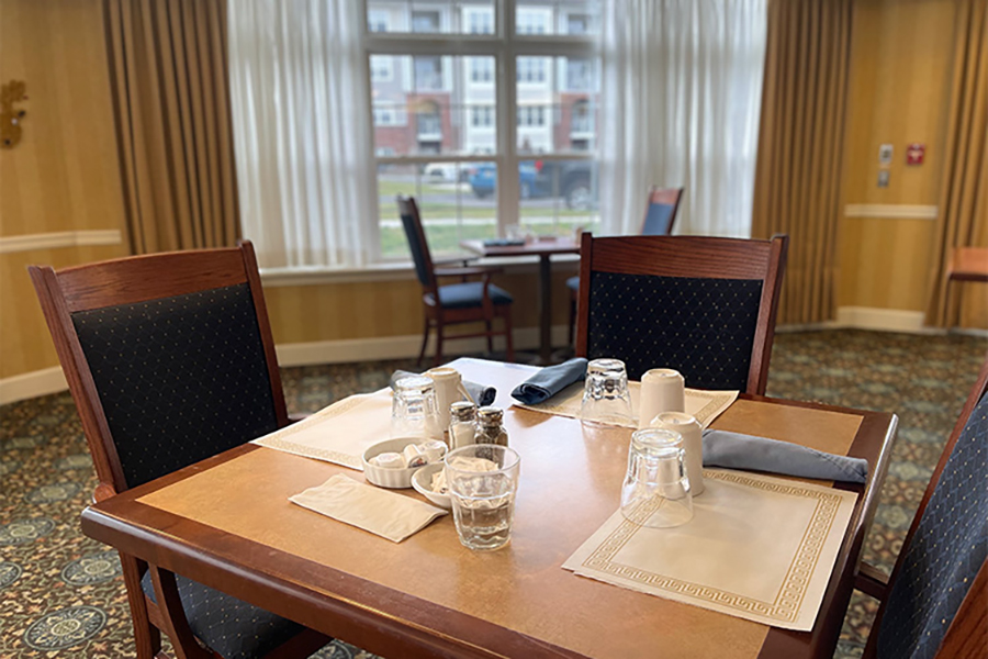 Cozy dining setup with tables, chairs, and window light.