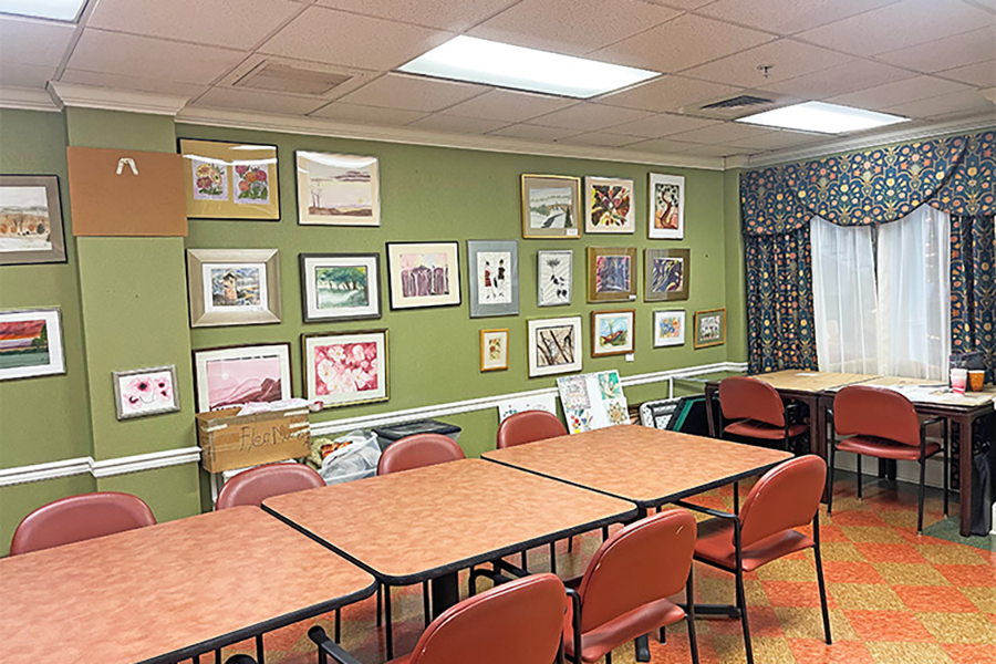 Art-filled room with tables and chairs, green walls.