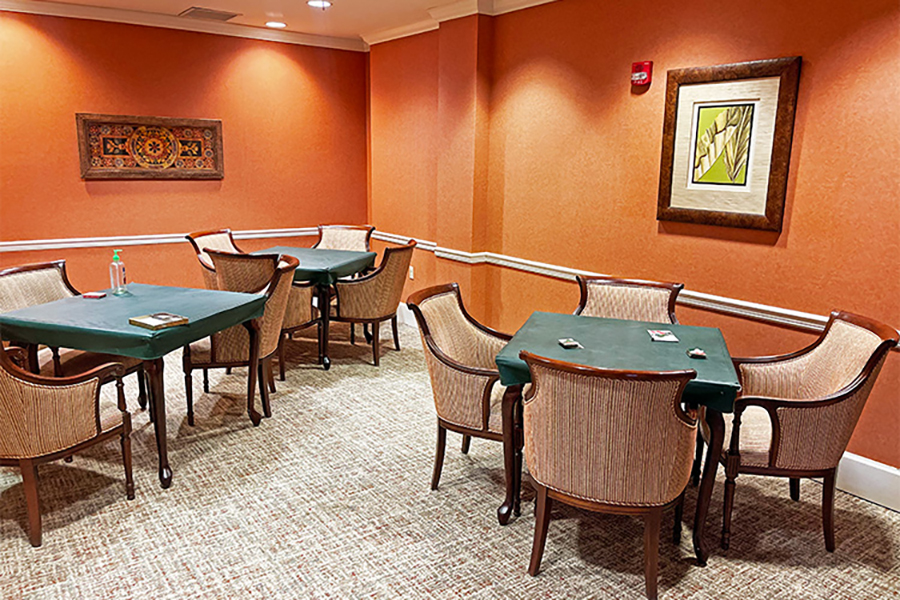Cozy room with tables and chairs, orange walls, artwork.