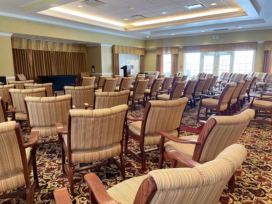 Empty conference room with rows of upholstered chairs.