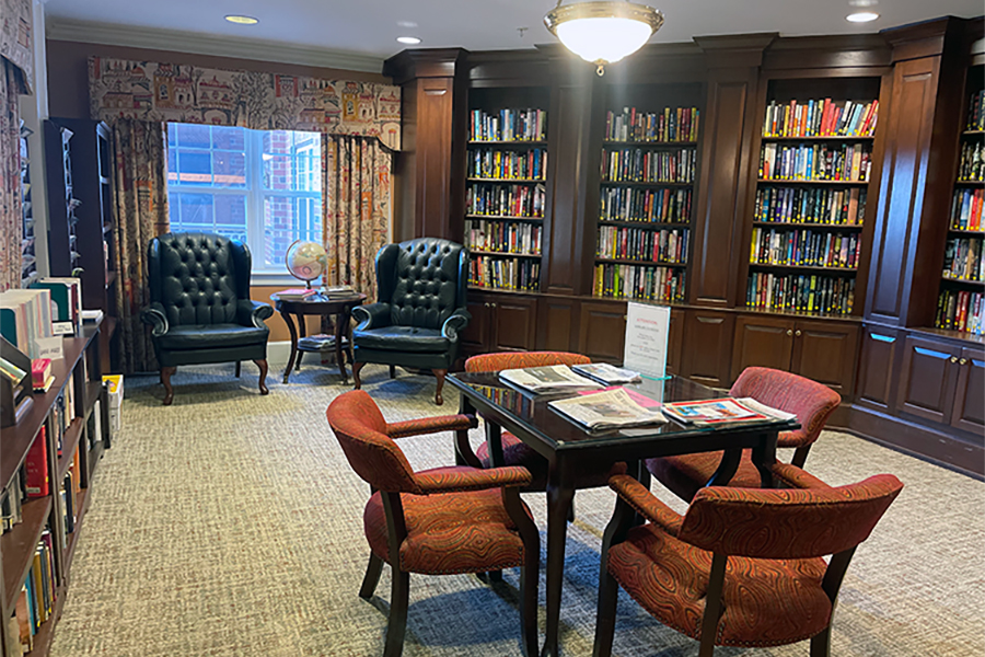 Cozy library with bookshelves, seating, and a table.