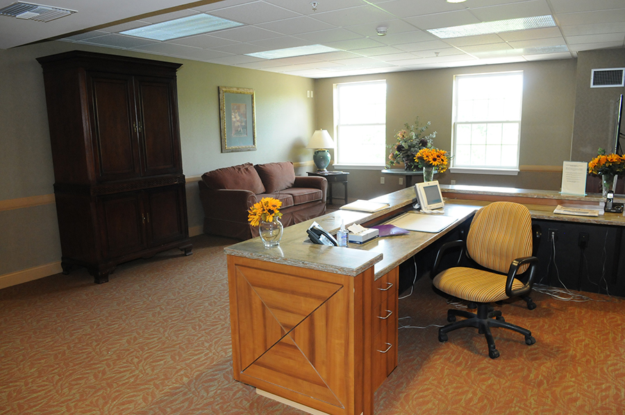 Cozy office space with desk, seating, and decorative flowers.