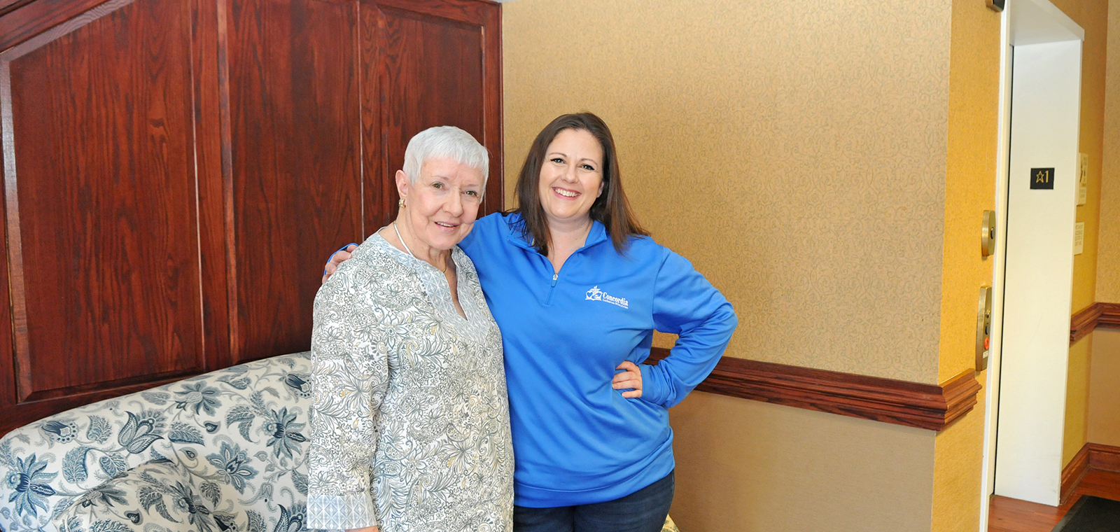 Two women smiling together in a cozy indoor setting.