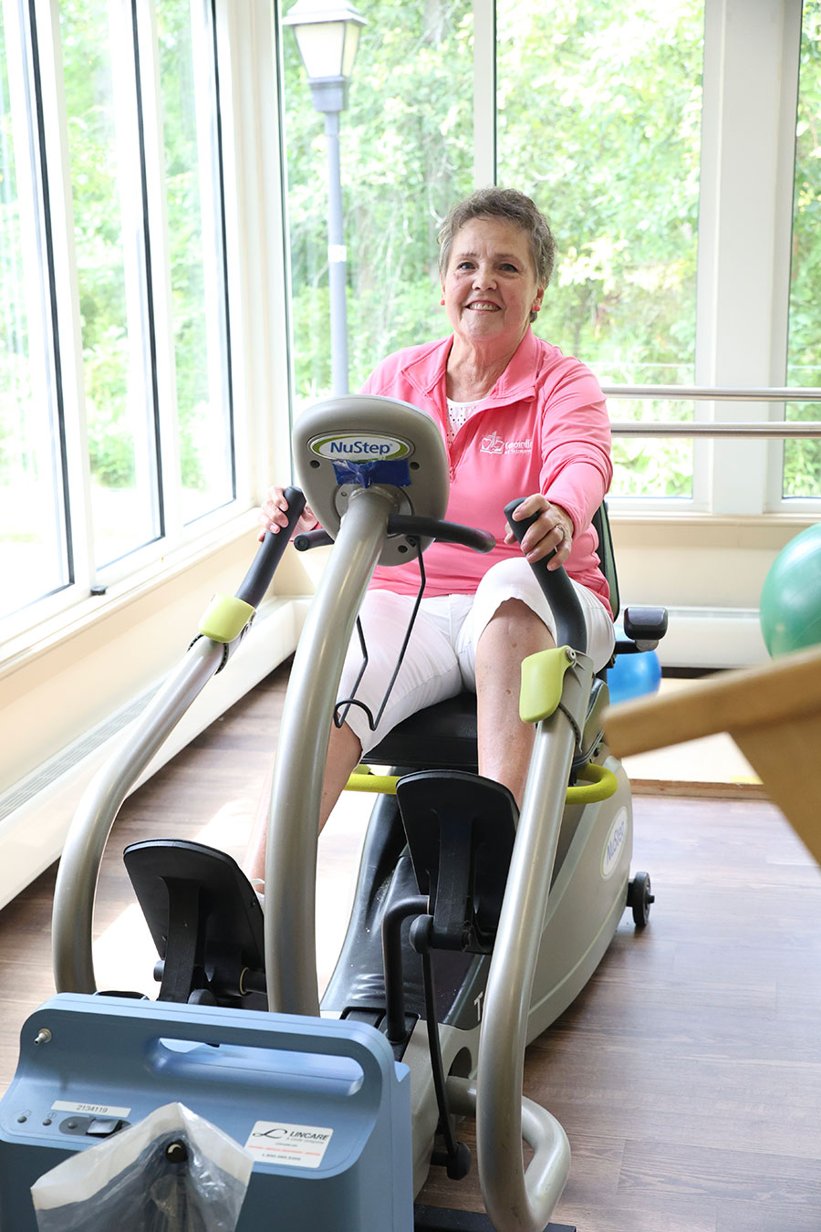 Woman exercising on a NuStep machine in bright room.
