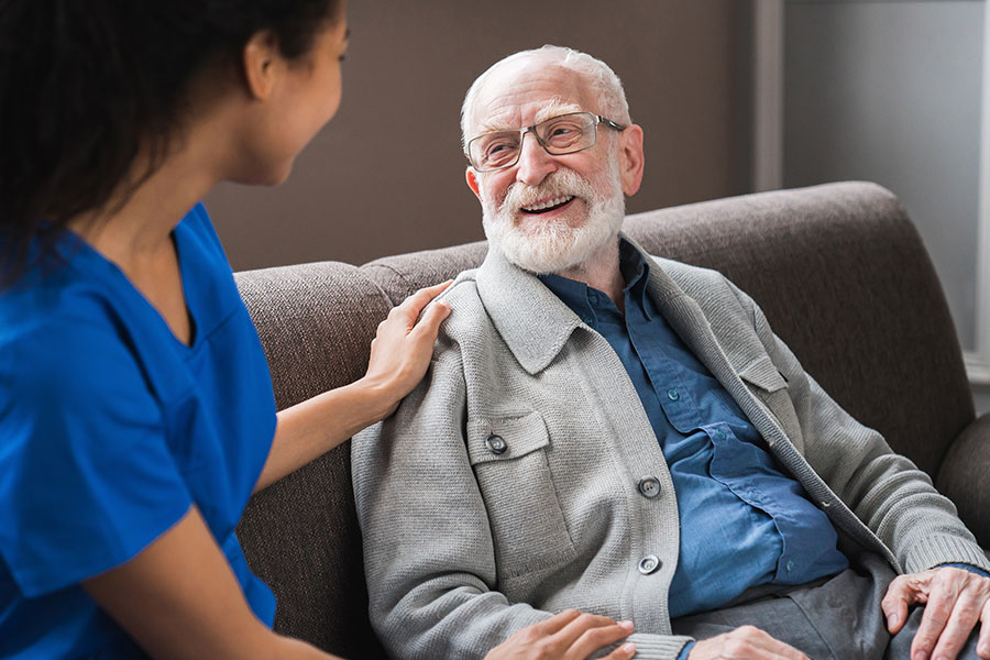 Smiling elderly man conversing with a caregiver.