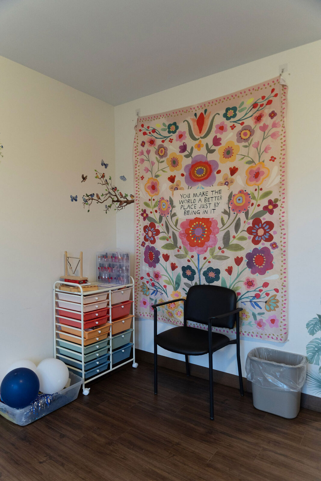Colorful wall tapestry with flowers and decorative items.