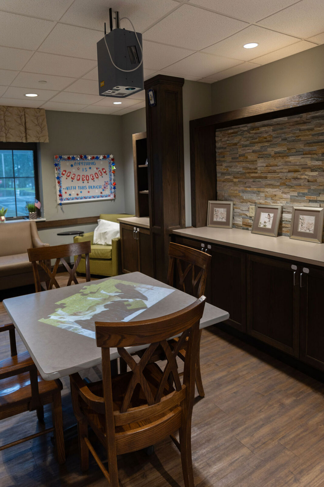 Cozy room with a table, chairs, and projector system.