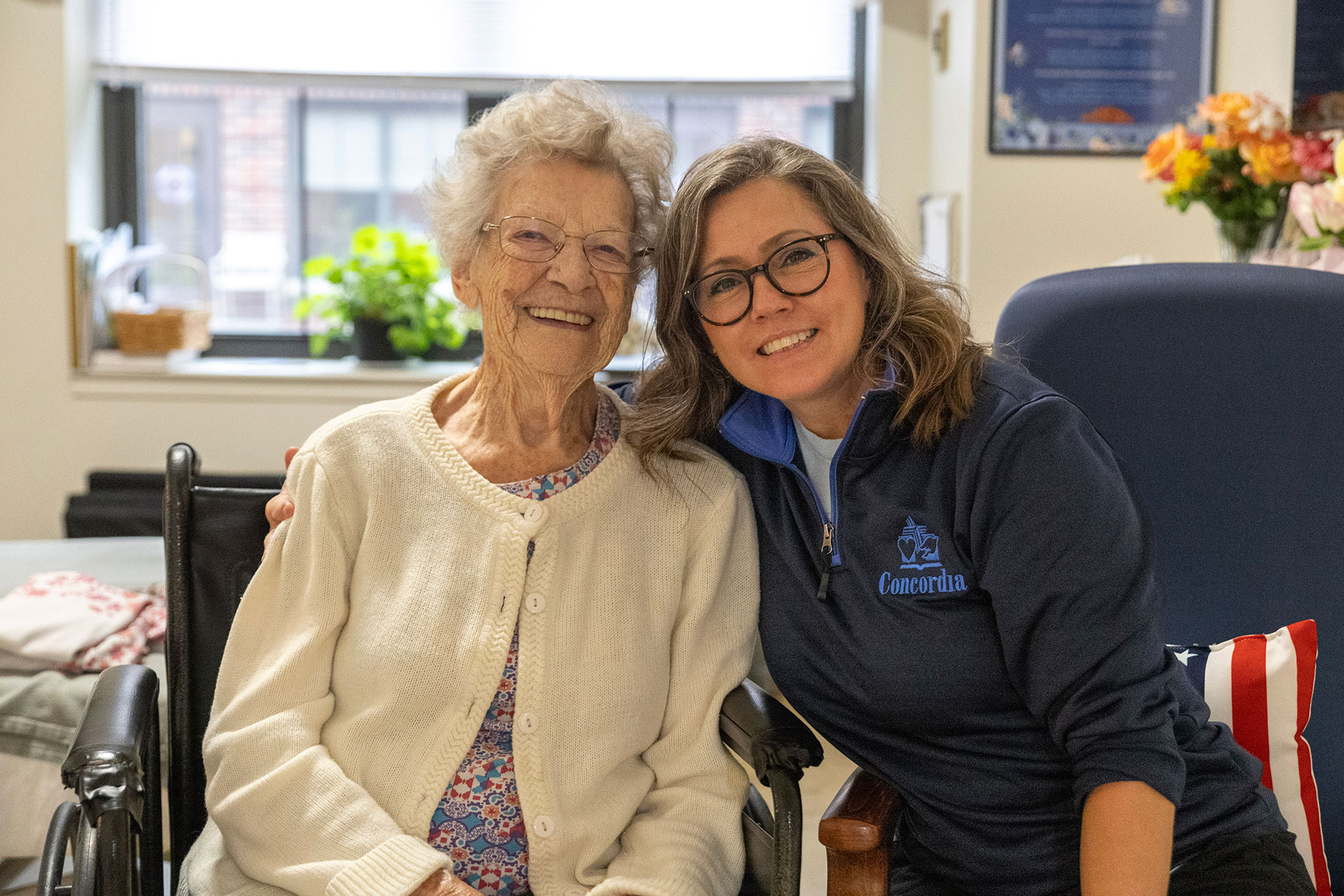 Two smiling women pose together in a cozy setting.