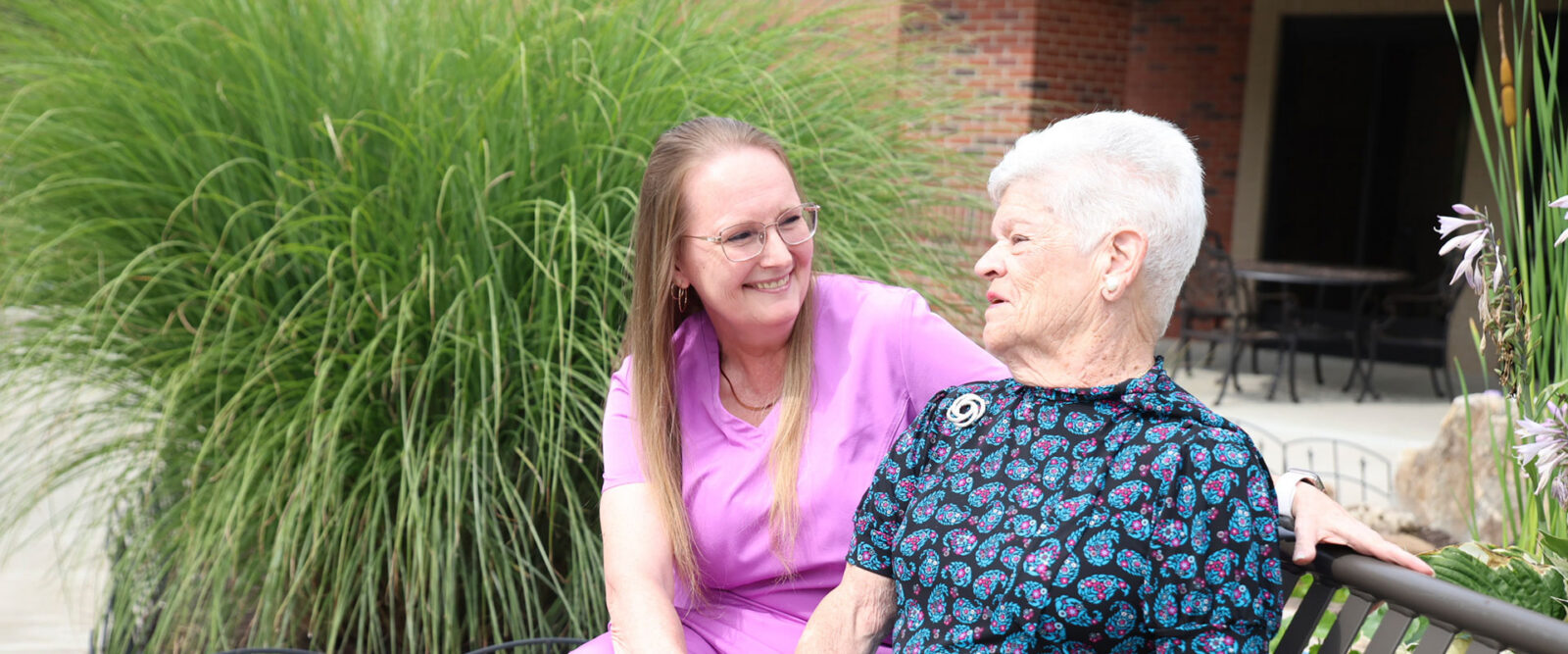 Two women sitting together, smiling, enjoying each other's company.
