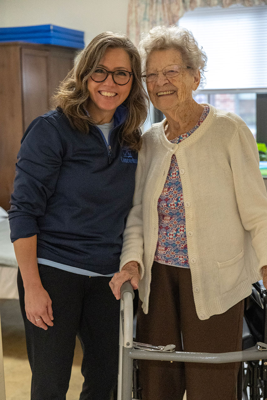 Two women smiling together, one using a walker.