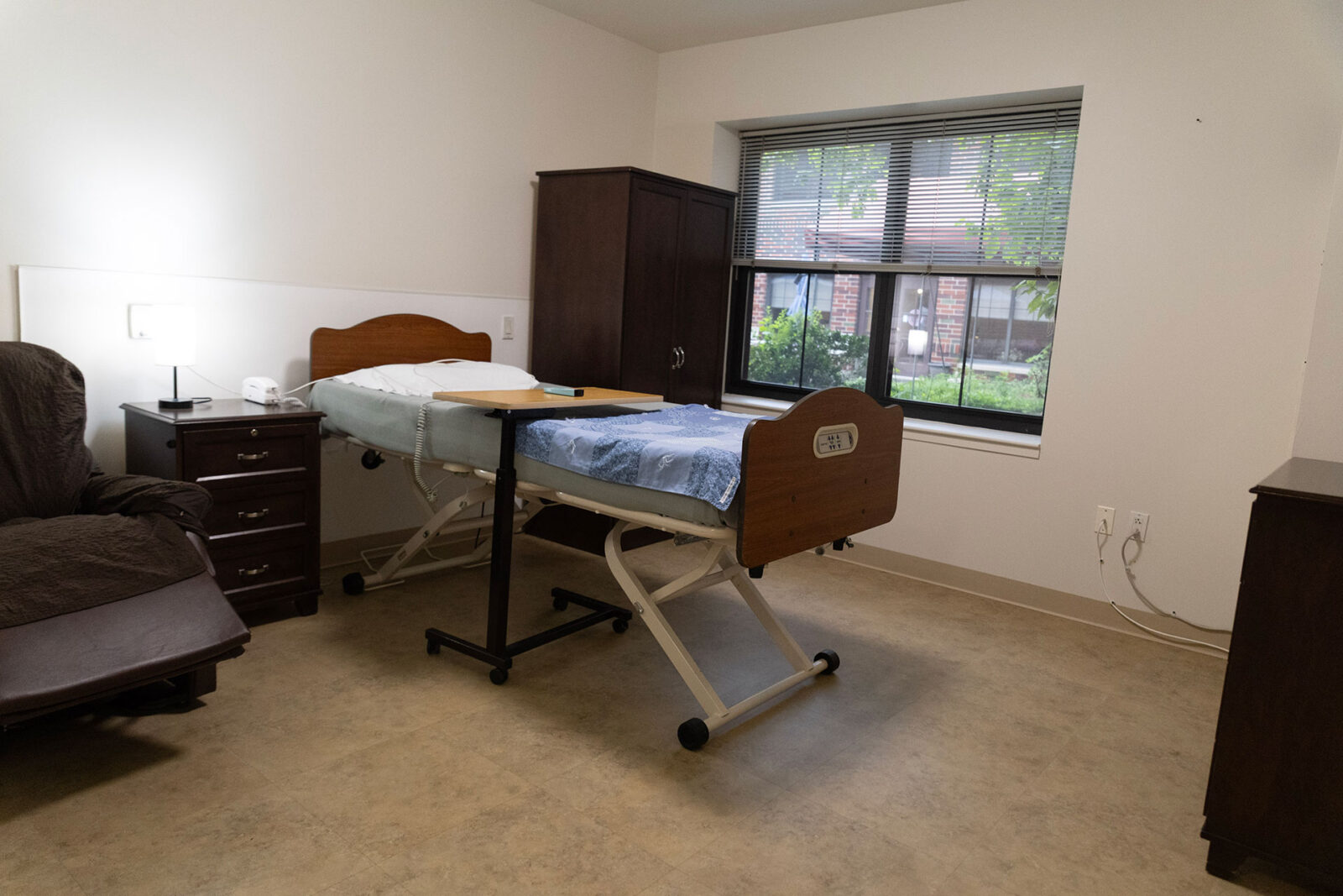 Hospital room with adjustable bed and bedside furniture.