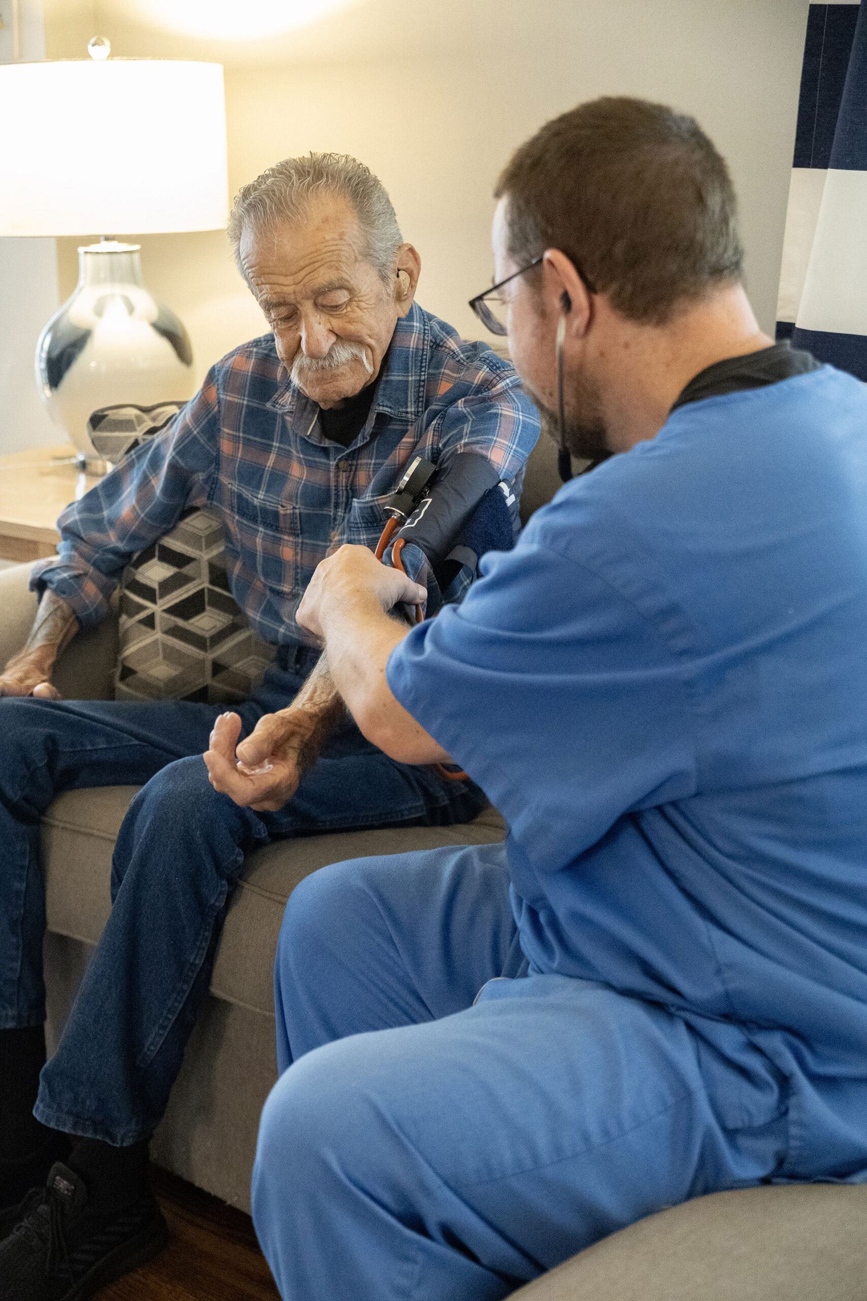 Medical professional taking a patient's blood pressure at home.