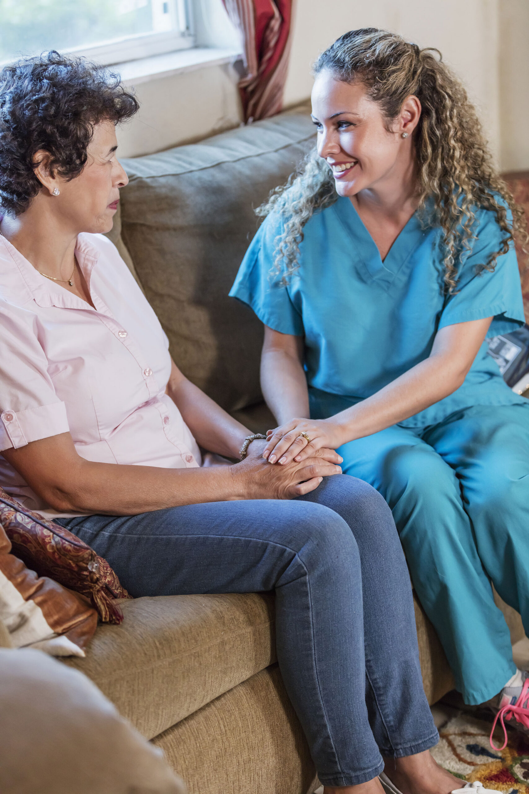 Two women sharing a supportive moment on a couch.