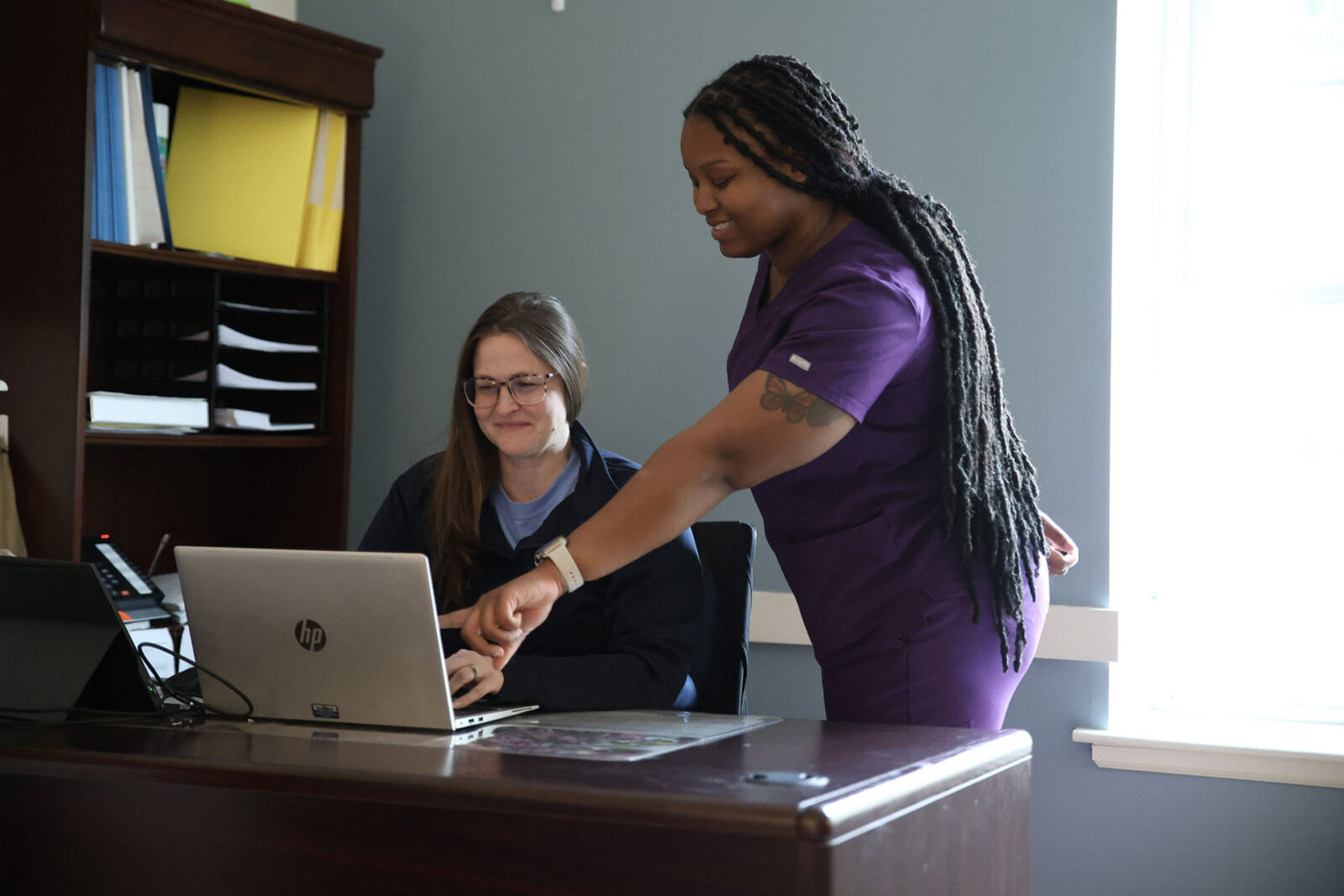 Two women collaborating at a desk with a laptop.