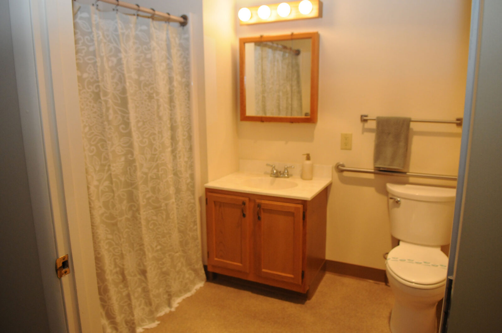 Bathroom with shower, sink, mirror, and toilet. Simple design.