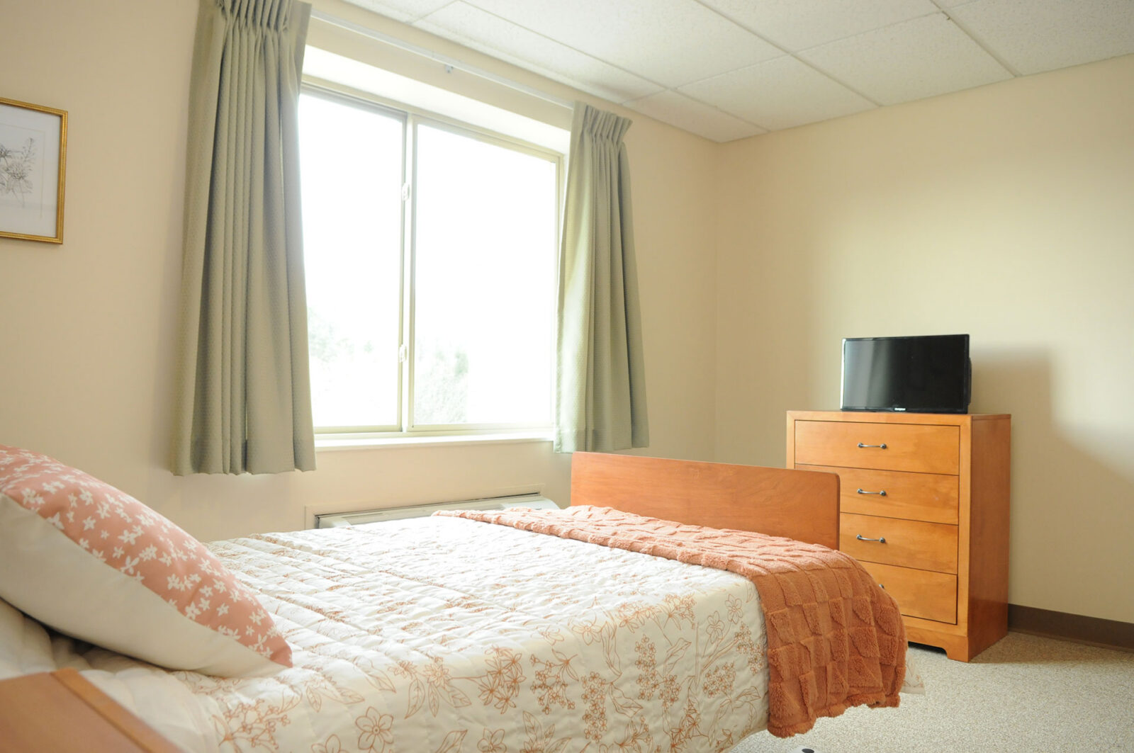Cozy bedroom with window, bed, and television.