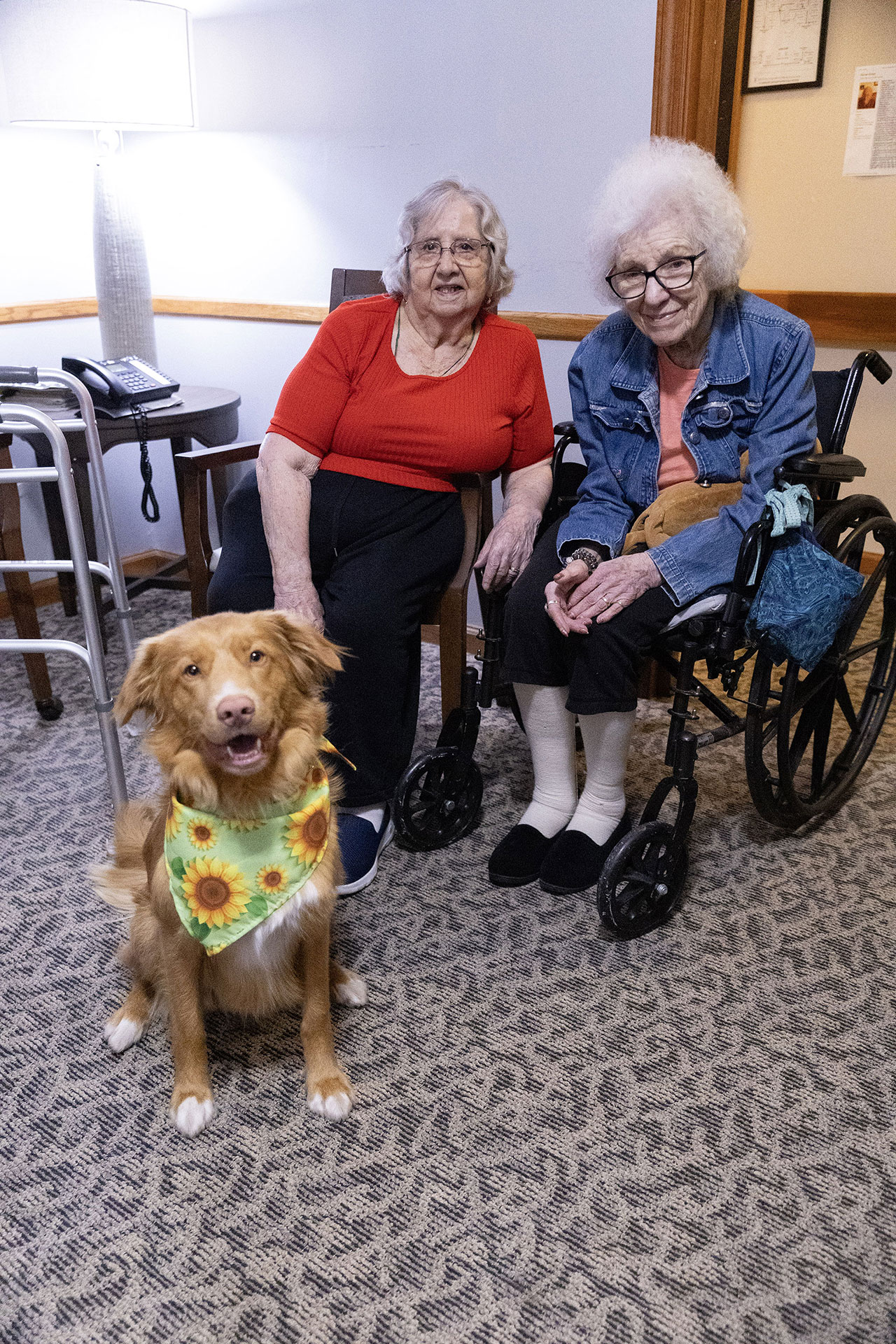 Two elderly women with a dog in a cozy setting.