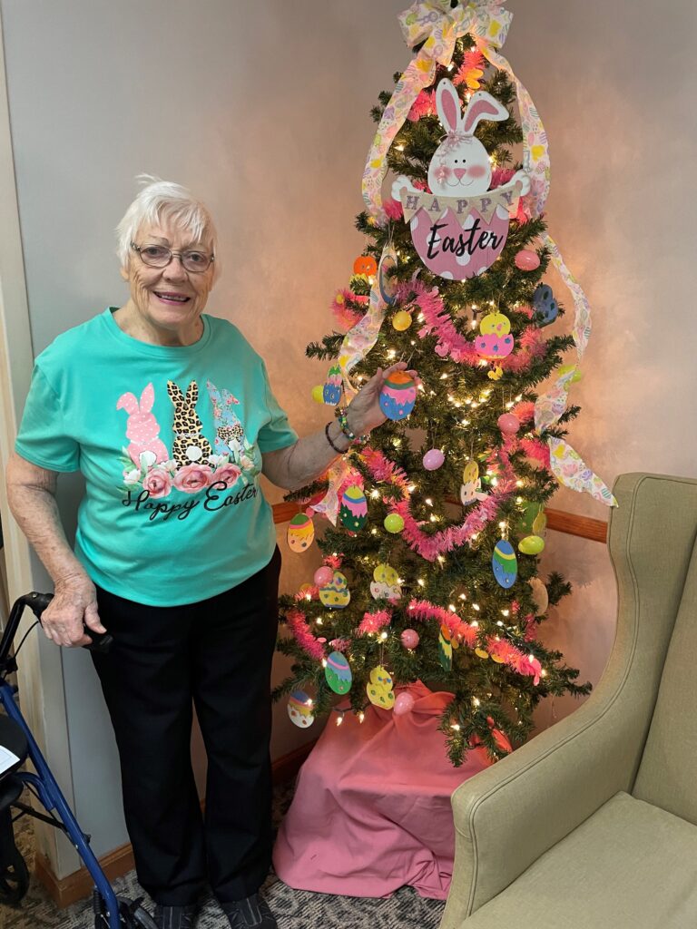 Concordia resident Virginia wearing an Easter shirt standing next to a Christmas tree decorated for Easter