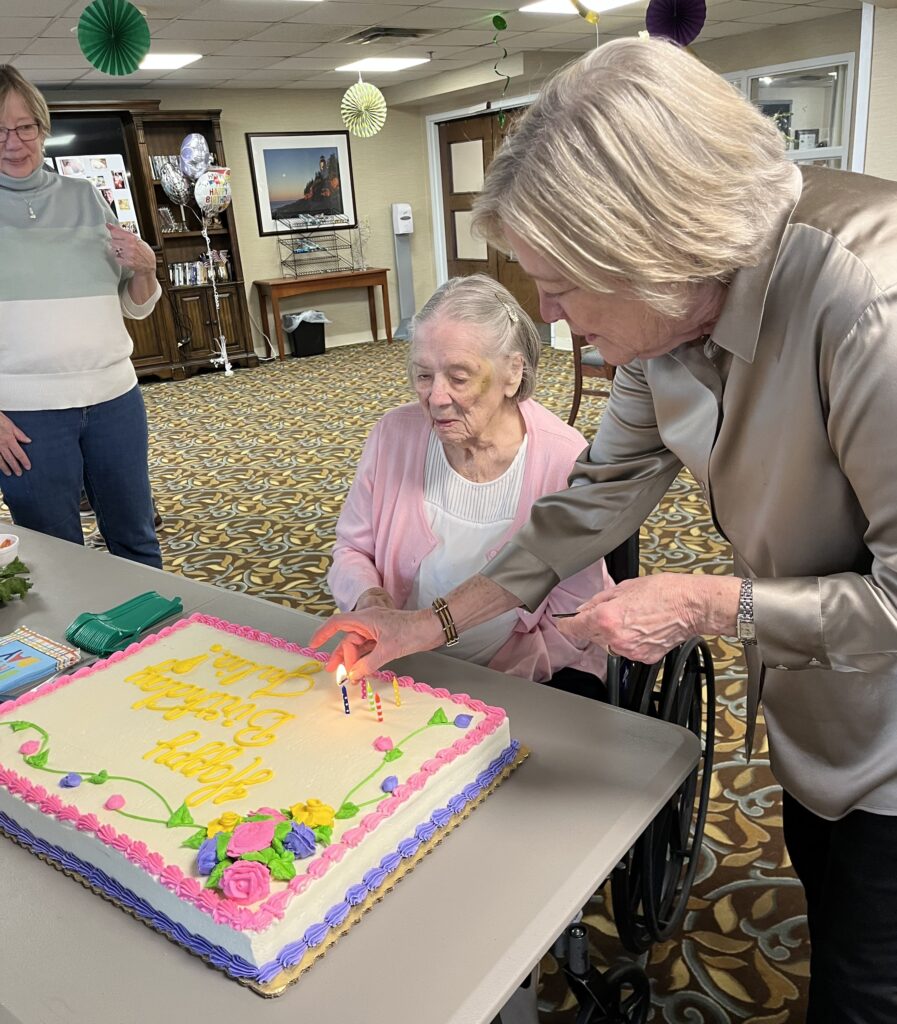 Concordia resident Julia looks at her 104th birthday cake while her daughter puts candles on it