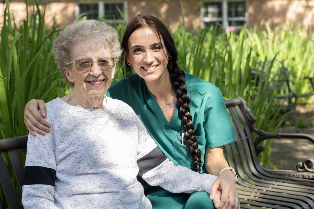 Resident Shirley L. enjoys sunshine in the courtyard with nurse aid Katie Wright.
