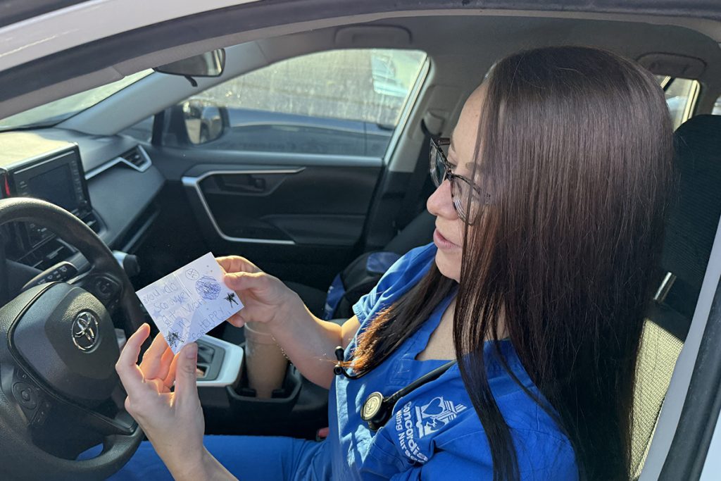 Mya shows a small handwritten card crafted by her daughter.