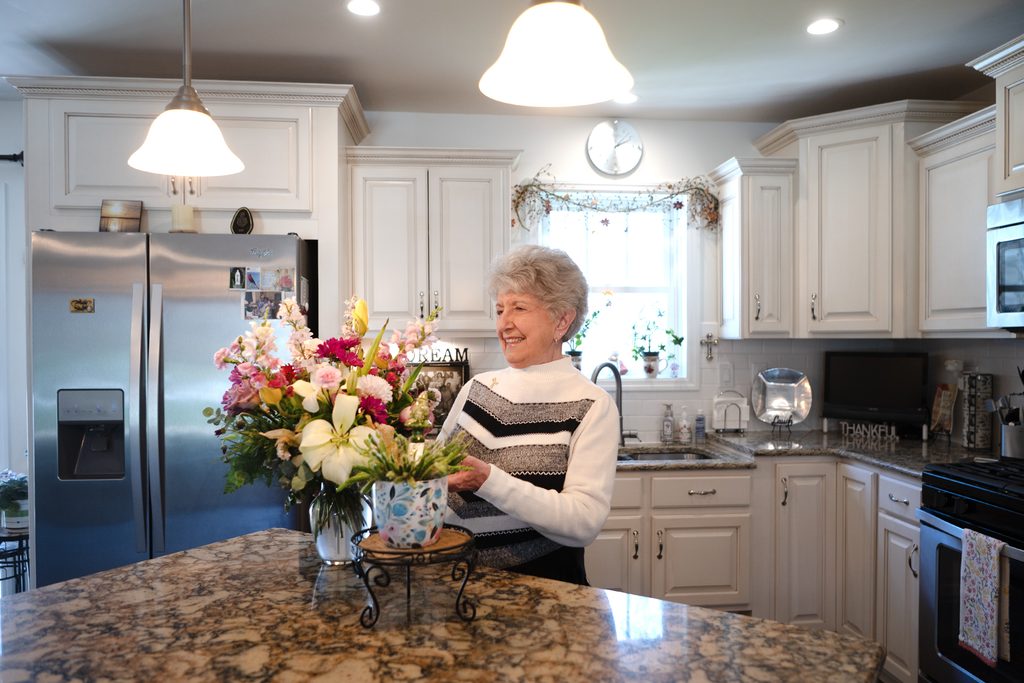 Concordia at Arbutus Park resident arranging flowers in the kitchen of her cottage