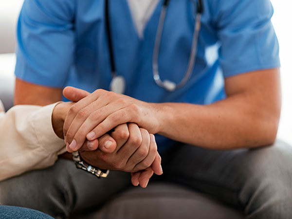 Volunteer holding hand of senior man, closeup. Close up of a nurse touching hand of a patient in a hospital ward. Caring nurse or doctor holding an elderly lady's hand with care.